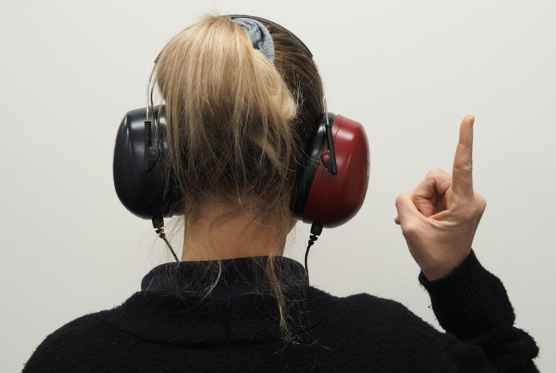 Paciente de fone de ouvido levantando o dedo durante a audiometria