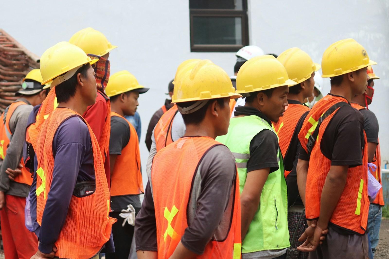 Equipe de trabalhadores de capacete e colete reunida